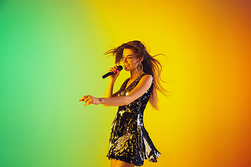 Image showing Caucasian female singer portrait isolated on gradient studio background in neon light