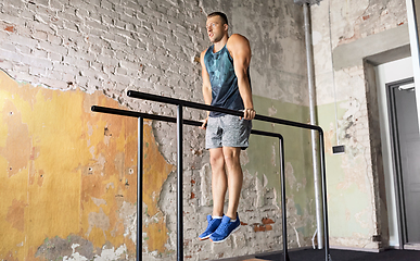 Image showing man doing triceps dip on parallel bars in gym