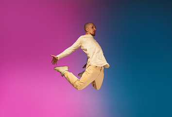 Image showing Stylish sportive caucasian man dancing hip-hop on colorful gradient background at dance hall in neon light.