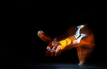 Image showing Young female volleyball player isolated on black studio background. Woman in sport\'s equipment training and practicing with fire shadow behind her