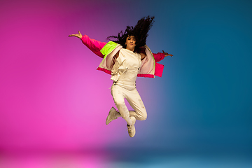 Image showing Stylish sportive caucasian woman dancing hip-hop on colorful gradient background at dance hall in neon light.