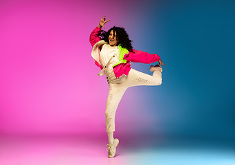 Image showing Stylish sportive caucasian woman dancing hip-hop on colorful gradient background at dance hall in neon light.