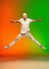 Image showing Stylish sportive caucasian man dancing hip-hop on colorful gradient background at dance hall in neon light.