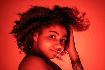 Image showing Beautiful african-american woman portrait isolated on red studio background in neon light, monochrome