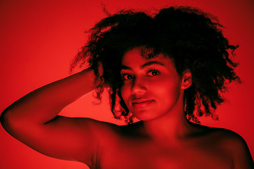 Image showing Beautiful african-american woman portrait isolated on red studio background in neon light, monochrome