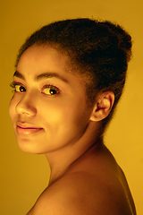 Image showing Beautiful african-american woman portrait isolated on yellow studio background in neon light, monochrome