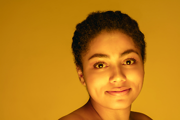 Image showing Beautiful african-american woman portrait isolated on yellow studio background in neon light, monochrome