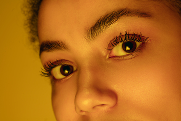 Image showing Beautiful african-american woman portrait isolated on yellow studio background in neon light, monochrome