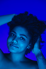 Image showing Beautiful african-american woman portrait isolated on blue studio background in neon light, monochrome