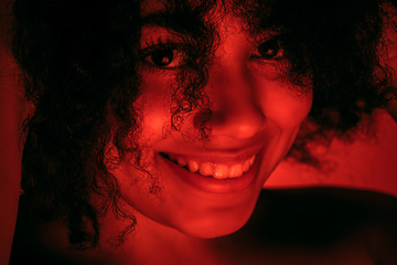 Image showing Beautiful african-american woman portrait isolated on red studio background in neon light, monochrome