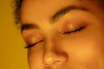 Image showing Beautiful african-american woman portrait isolated on yellow studio background in neon light, monochrome