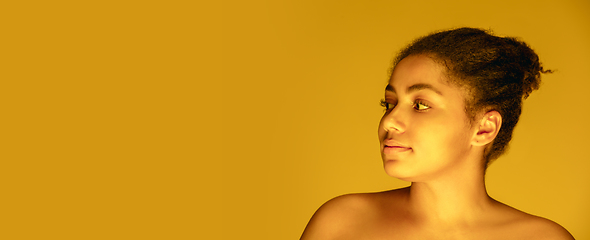 Image showing Beautiful african-american woman portrait isolated on yellow studio background in neon light, monochrome