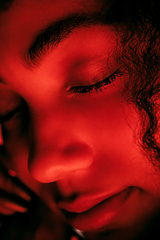 Image showing Beautiful african-american woman portrait isolated on red studio background in neon light, monochrome