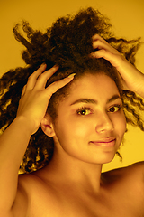 Image showing Beautiful african-american woman portrait isolated on yellow studio background in neon light, monochrome