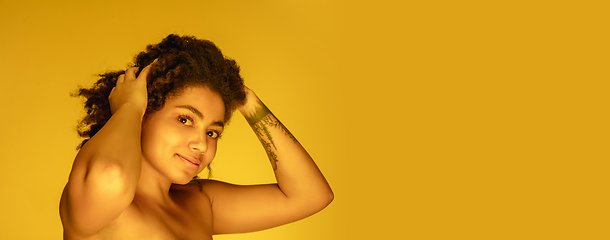 Image showing Beautiful african-american woman portrait isolated on yellow studio background in neon light, monochrome
