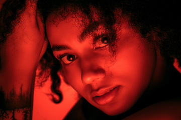 Image showing Beautiful african-american woman portrait isolated on red studio background in neon light, monochrome