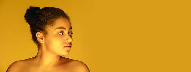 Image showing Beautiful african-american woman portrait isolated on yellow studio background in neon light, monochrome