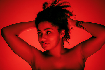 Image showing Beautiful african-american woman portrait isolated on red studio background in neon light, monochrome