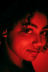 Image showing Beautiful african-american woman portrait isolated on red studio background in neon light, monochrome