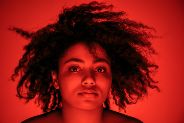 Image showing Beautiful african-american woman portrait isolated on red studio background in neon light, monochrome