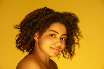 Image showing Beautiful african-american woman portrait isolated on yellow studio background in neon light, monochrome