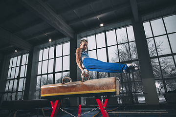 Image showing Little male gymnast training in gym, flexible and active. Caucasian fit little boy, athlete in sportswear practicing in exercises for strength, balance.