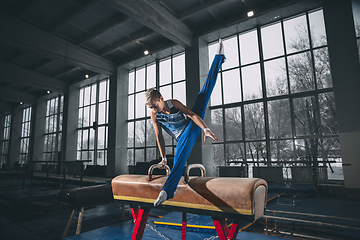 Image showing Little male gymnast training in gym, flexible and active. Caucasian fit little boy, athlete in sportswear practicing in exercises for strength, balance.