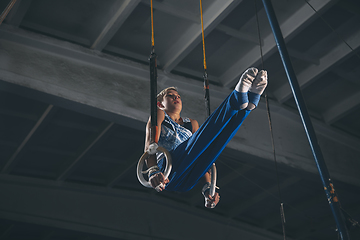 Image showing Little male gymnast training in gym, flexible and active. Caucasian fit little boy, athlete in sportswear practicing in exercises for strength, balance.