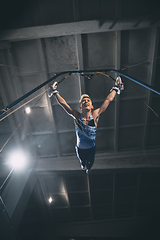 Image showing Little male gymnast training in gym, flexible and active. Caucasian fit little boy, athlete in sportswear practicing in exercises for strength, balance.