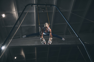 Image showing Little male gymnast training in gym, flexible and active. Caucasian fit little boy, athlete in sportswear practicing in exercises for strength, balance.