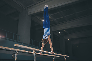 Image showing Little male gymnast training in gym, flexible and active. Caucasian fit little boy, athlete in sportswear practicing in exercises for strength, balance.