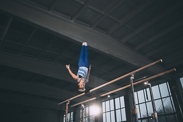 Image showing Little male gymnast training in gym, flexible and active. Caucasian fit little boy, athlete in sportswear practicing in exercises for strength, balance.