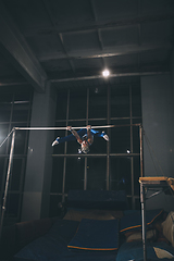 Image showing Little male gymnast training in gym, flexible and active. Caucasian fit little boy, athlete in sportswear practicing in exercises for strength, balance.