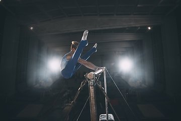 Image showing Little male gymnast training in gym, flexible and active. Caucasian fit little boy, athlete in sportswear practicing in exercises for strength, balance.