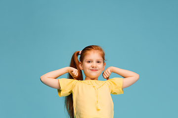 Image showing Happy caucasian little girl isolated on blue studio background. Looks happy, cheerful, sincere. Copyspace. Childhood, education, emotions concept