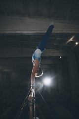 Image showing Little male gymnast training in gym, flexible and active. Caucasian fit little boy, athlete in sportswear practicing in exercises for strength, balance.