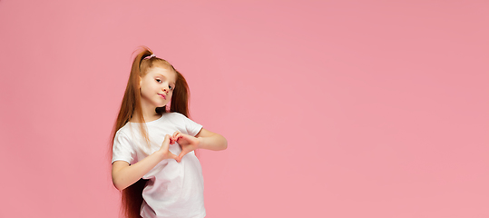 Image showing Happy caucasian little girl isolated on pink studio background. Looks happy, cheerful, sincere. Copyspace. Childhood, education, emotions concept