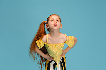 Image showing Happy caucasian little girl isolated on blue studio background. Looks happy, cheerful, sincere. Copyspace. Childhood, education, emotions concept