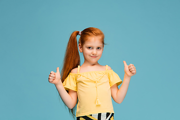 Image showing Happy caucasian little girl isolated on blue studio background. Looks happy, cheerful, sincere. Copyspace. Childhood, education, emotions concept