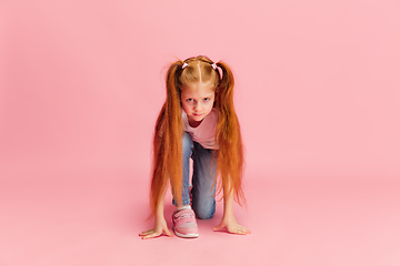 Image showing Happy caucasian little girl isolated on pink studio background. Looks happy, cheerful, sincere. Copyspace. Childhood, education, emotions concept