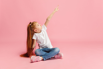 Image showing Happy caucasian little girl isolated on pink studio background. Looks happy, cheerful, sincere. Copyspace. Childhood, education, emotions concept