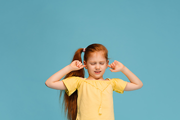 Image showing Happy caucasian little girl isolated on blue studio background. Looks happy, cheerful, sincere. Copyspace. Childhood, education, emotions concept