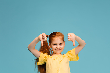 Image showing Happy caucasian little girl isolated on blue studio background. Looks happy, cheerful, sincere. Copyspace. Childhood, education, emotions concept