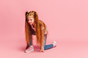 Image showing Happy caucasian little girl isolated on pink studio background. Looks happy, cheerful, sincere. Copyspace. Childhood, education, emotions concept