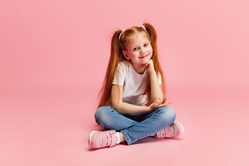 Image showing Happy caucasian little girl isolated on pink studio background. Looks happy, cheerful, sincere. Copyspace. Childhood, education, emotions concept