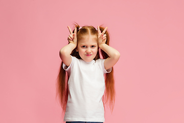 Image showing Happy caucasian little girl isolated on pink studio background. Looks happy, cheerful, sincere. Copyspace. Childhood, education, emotions concept