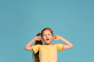 Image showing Happy caucasian little girl isolated on blue studio background. Looks happy, cheerful, sincere. Copyspace. Childhood, education, emotions concept