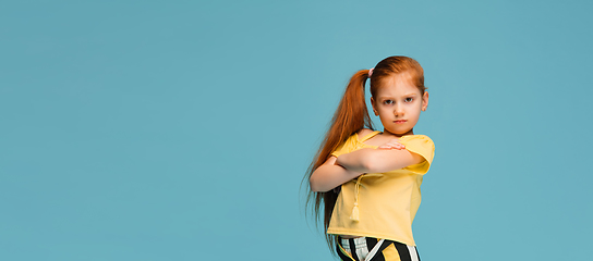 Image showing Happy caucasian little girl isolated on blue studio background. Looks happy, cheerful, sincere. Copyspace. Childhood, education, emotions concept