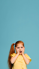 Image showing Happy caucasian little girl isolated on blue studio background. Looks happy, cheerful, sincere. Copyspace. Childhood, education, emotions concept