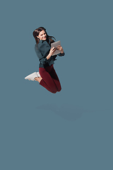 Image showing High angle view of young woman on blue studio background. Girl in motion or movement. Human emotions and facial expressions concept